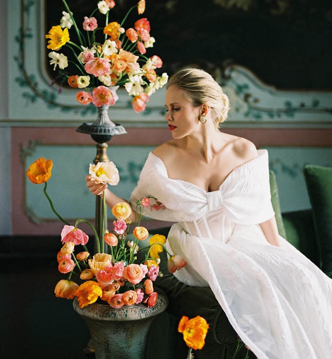 Model wearing a gown and sitting near flowers